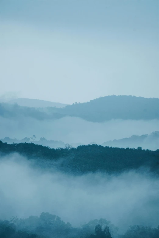 a view of the mountains from the top of a hill, an album cover, trending on unsplash, romanticism, pale blue fog, stacks, blue gray, blue