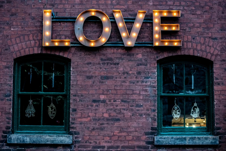 the word love is lit up on the side of a brick building, by Bradley Walker Tomlin, pexels contest winner, old signs, window lights, tiffany dover, profile image