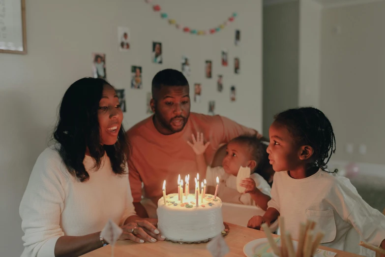 a family celebrating a birthday with a cake, pexels contest winner, ( ( dark skin ) ), fan favorite, white candles, beautiful surroundings