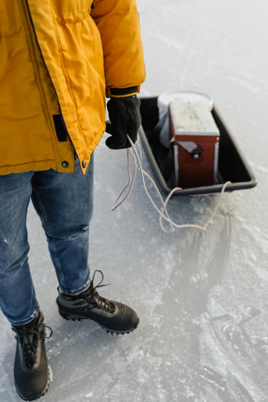 a man in a yellow jacket is pulling a sled, by Veikko Törmänen, trending on pexels, plasticien, cords and wires, ice fish shape, grey, rectangle