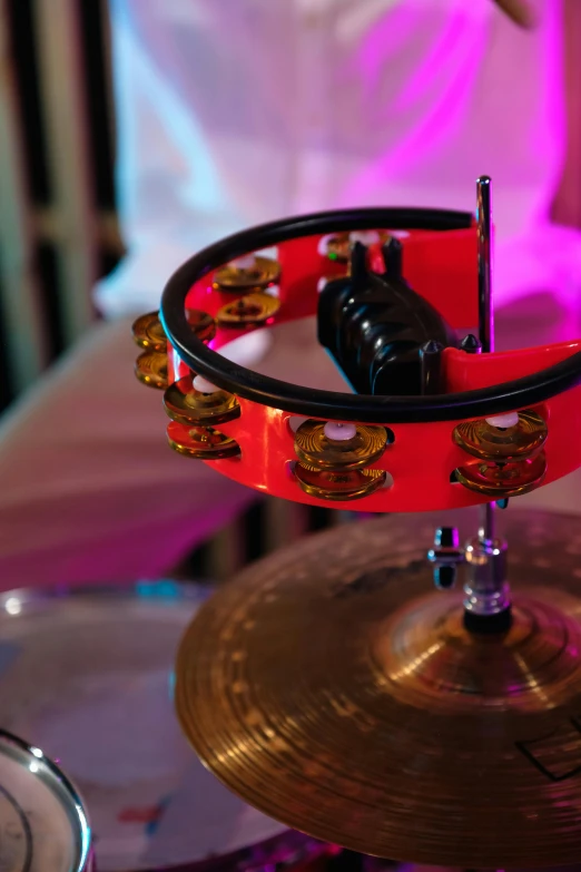 a close up of a drum set on a table, kinetic art, ring lighting, crimson themed, coloured, bells