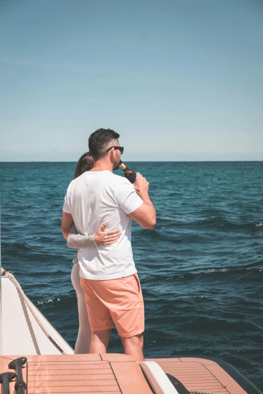 a man and a woman standing on a boat, pexels contest winner, half turned around, viewed from the ocean, drinking, hugging