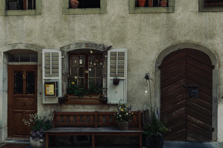 a wooden bench sitting in front of a building, pexels contest winner, renaissance, secretly on a village, muted brown, swiss architecture, flower shop scene