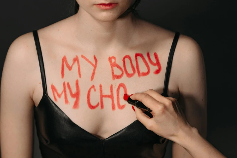 a woman with red writing on her chest, inspired by Vanessa Beecroft, trending on pexels, chiho, chaos, hand-drawn, cruelty
