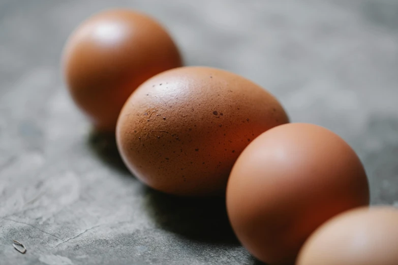 a group of eggs sitting on top of a table, a picture, trending on pexels, brown, from the side, slightly muscular, amanda lilleston