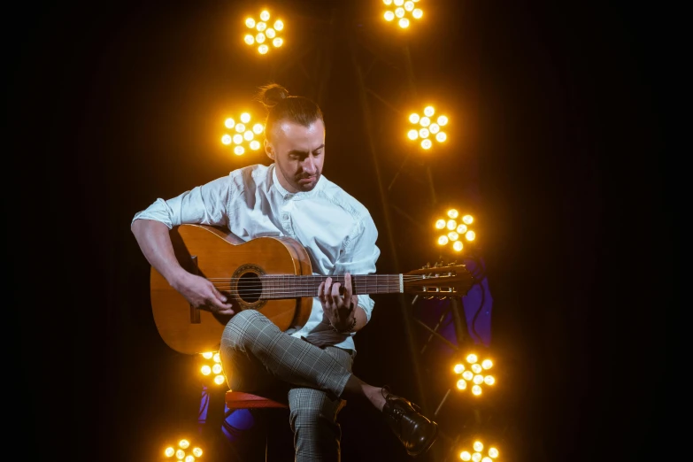 a man sitting on a stool playing a guitar, antipodeans, advanced stage lighting, square, liam brazier, artem