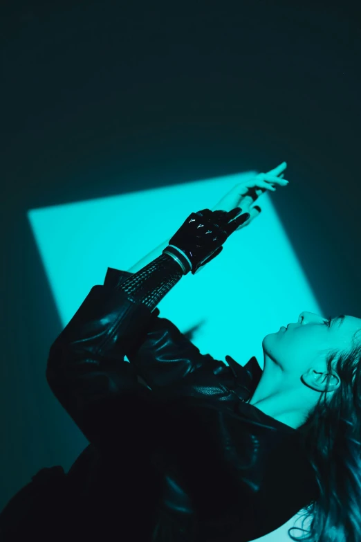 a woman standing in front of a blue light, an album cover, inspired by Elsa Bleda, trending on pexels, bauhaus, dressed in black leather, light emitting from fingertips, profile image, doing a sassy pose