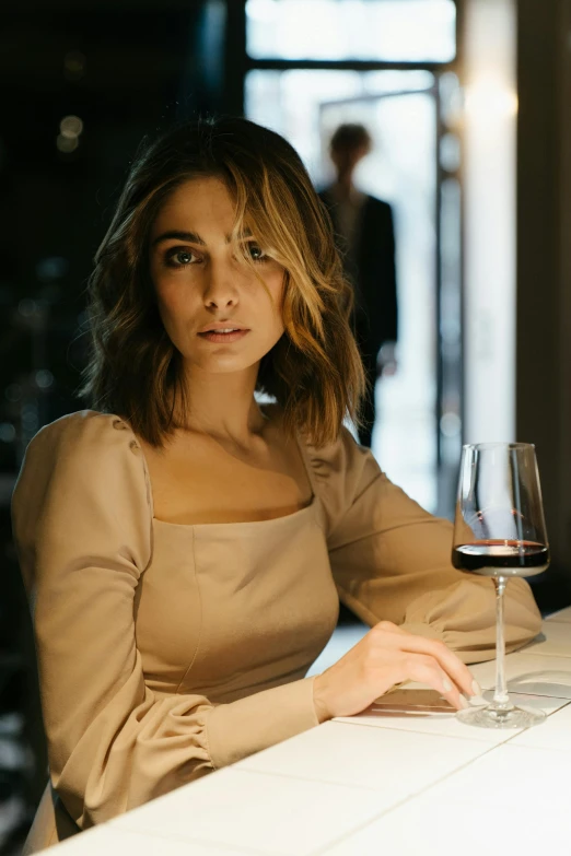 a woman sitting at a table with a glass of wine, a portrait, by Seb McKinnon, pexels contest winner, olivia culpo, serious business, casually dressed, a handsome