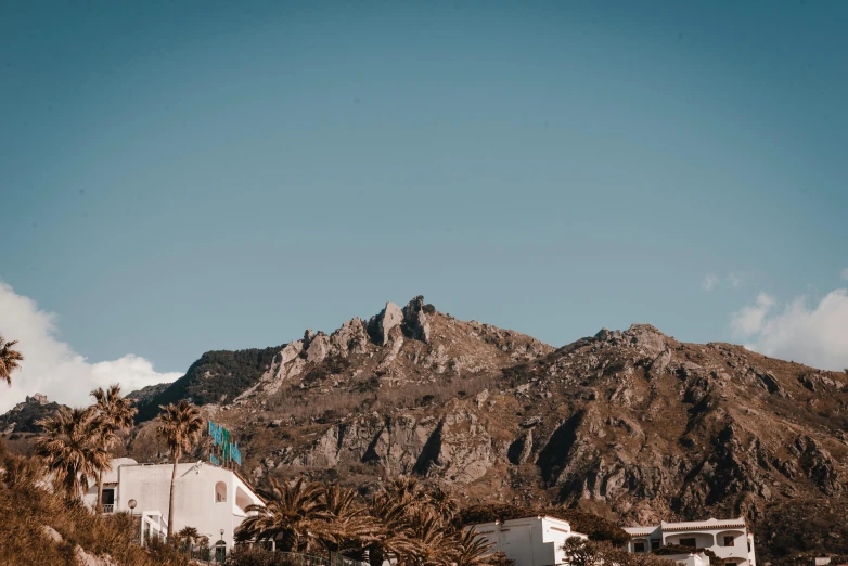 a beach with palm trees and a mountain in the background, by Lee Loughridge, pexels contest winner, art nouveau, white houses, background image, marbella, standing on top of a mountain