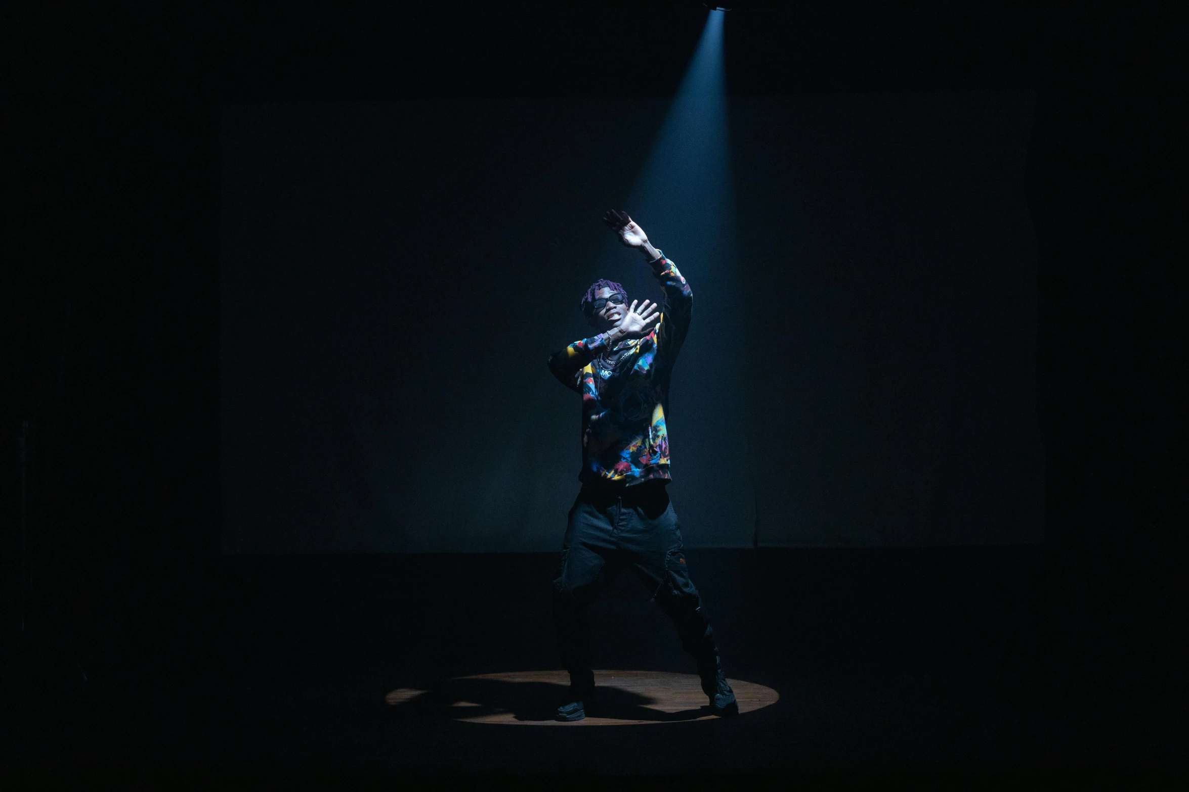 a man standing on top of a stage under a spotlight, unsplash, holography, portrait of combat dancer, riyahd cassiem, dark. studio lighting, masked person in corner