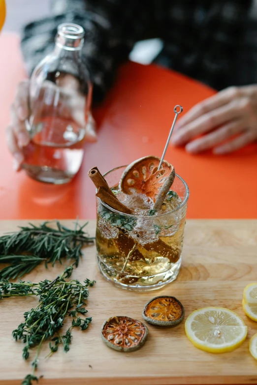 a person sitting at a table with a glass of alcohol, by Julia Pishtar, trending on pexels, dried herbs, stick and poke, square, smoked layered