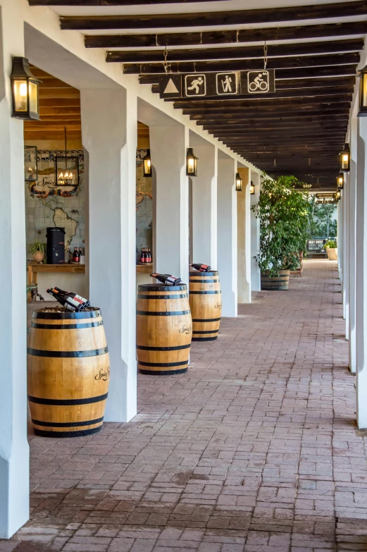 a row of wooden barrels sitting on top of a brick floor, courtyard walkway, hollister ranch, colonnade, wine