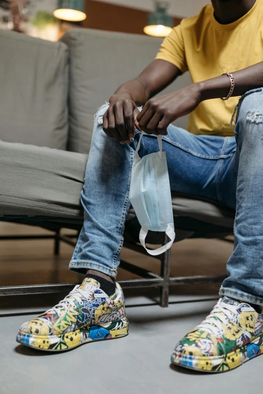 a man sitting on a couch holding a bag, trending on pexels, hyperrealism, wearing white sneakers, finely masked, jean and multicolor shoes, jaylen brown