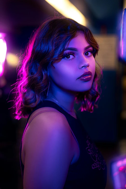 a woman standing in front of a neon light, trending on pexels, isabela moner, purple lipstick, dramatic lighting. stylized, coloured photo