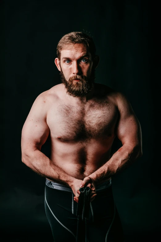 a shirtless man standing in front of a black background, inspired by Gwilym Prichard, curled beard, wrestler, pendleton ward, professional photo