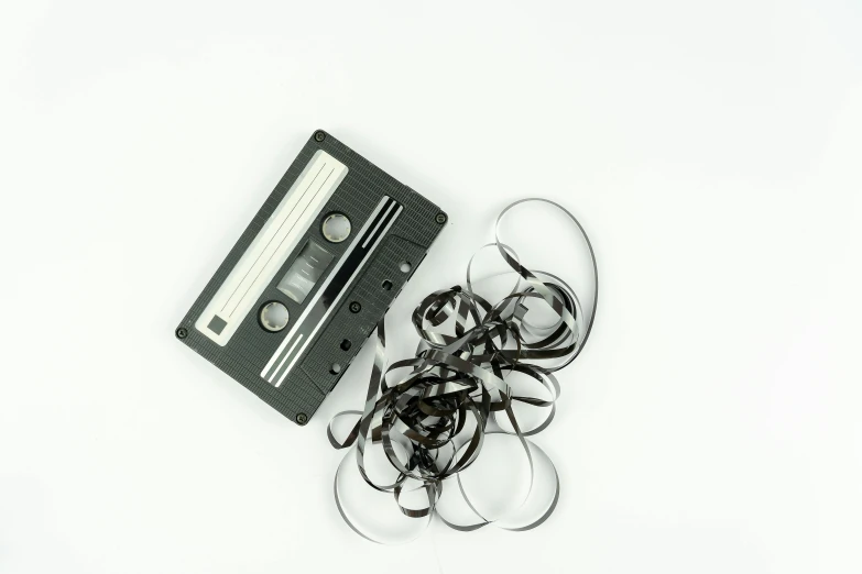 a black and white photo of a cassette and glasses, pexels, fluxus, black color on white background, ribbon, mixing, synthetic materials