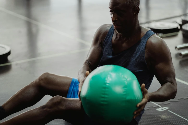 a man sitting on the floor holding a green ball, local gym, profile image, malcolm hart, mc ride