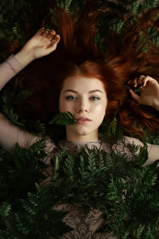 a woman laying on top of a lush green field, an album cover, inspired by Elsa Bleda, trending on pexels, renaissance, redhead girl, ferns, ignant, lorde