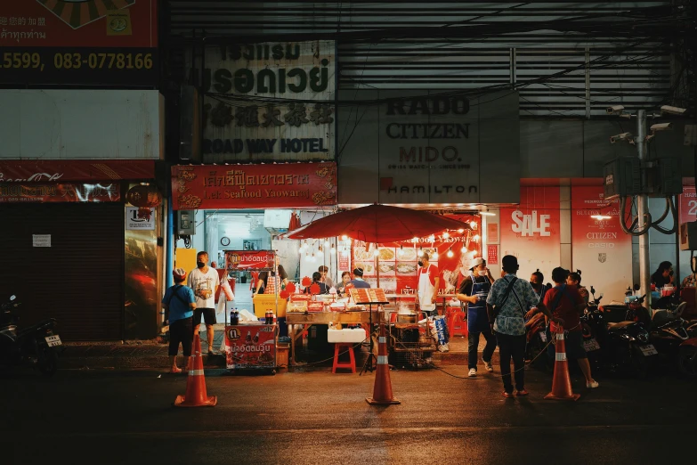 a group of people standing in front of a food stand, pexels contest winner, with orange street lights, thailand, red and white neon, people outside eating meals