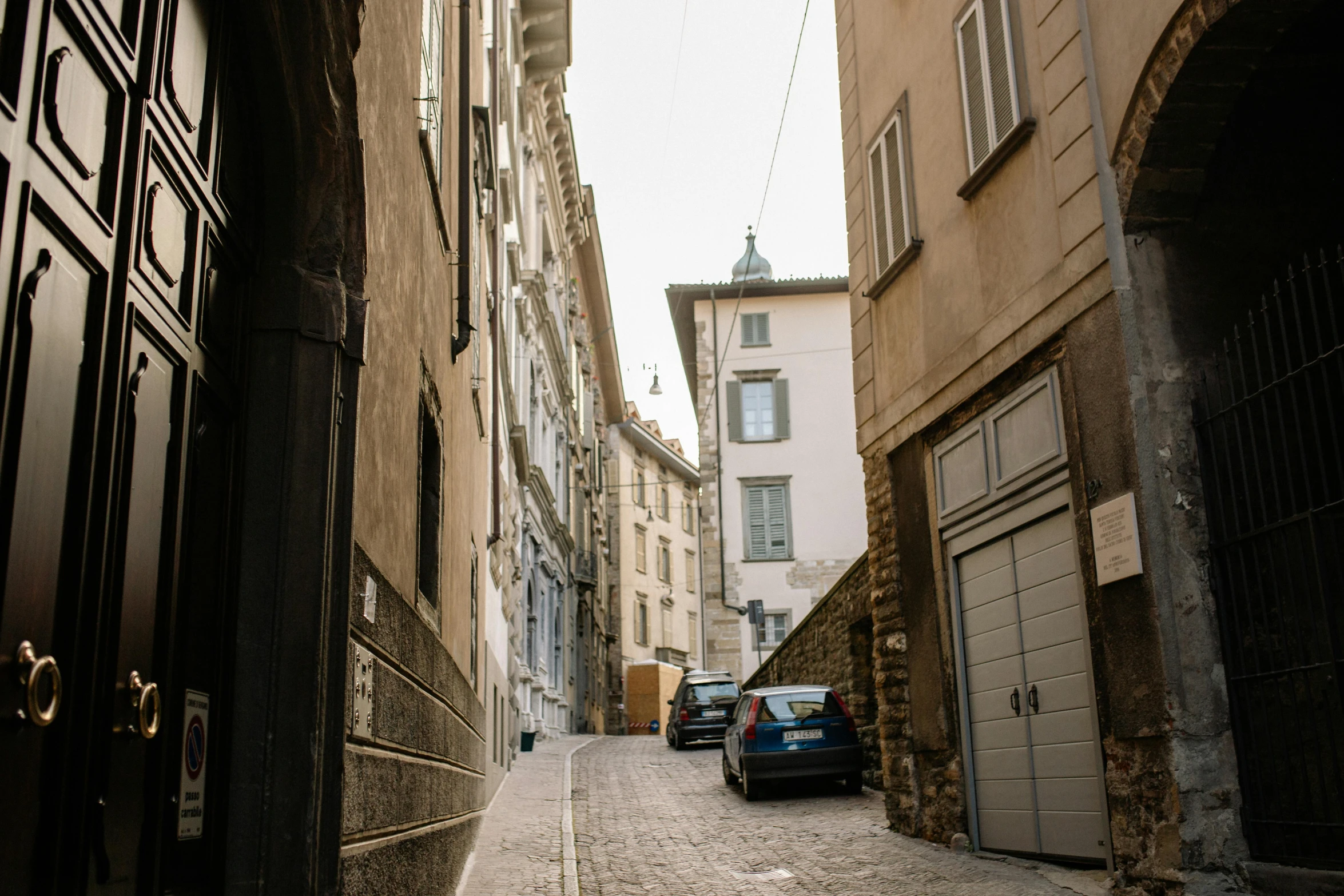 a car is parked on a cobblestone street, pexels contest winner, renaissance, white pale concrete city, portrait image, italian, view from across the street