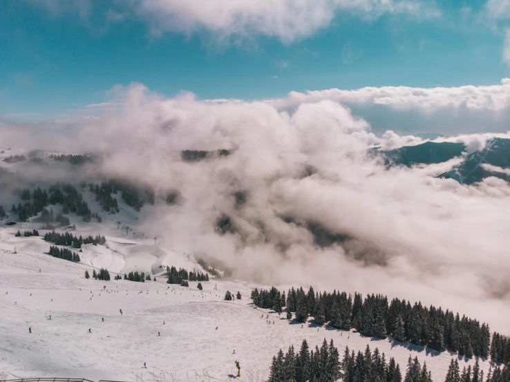 a group of people riding skis on top of a snow covered slope, by Emma Andijewska, pexels contest winner, castle made of clouds, cotton clouds, snow on trees and ground, view above the clouds