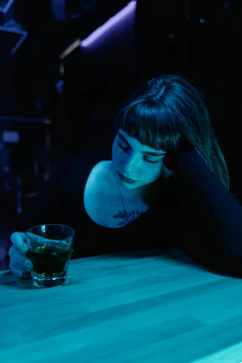 a woman sitting at a bar with a drink in her hand, inspired by Elsa Bleda, pexels, renaissance, sad face, blue light, cynthwave, in a pitch black room