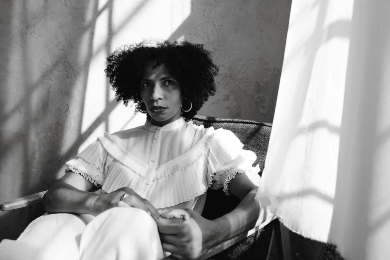 a black and white photo of a woman sitting in a chair, inspired by Carrie Mae Weems, pexels, renaissance, curly afro, summer light, delicate androgynous prince, white clothes