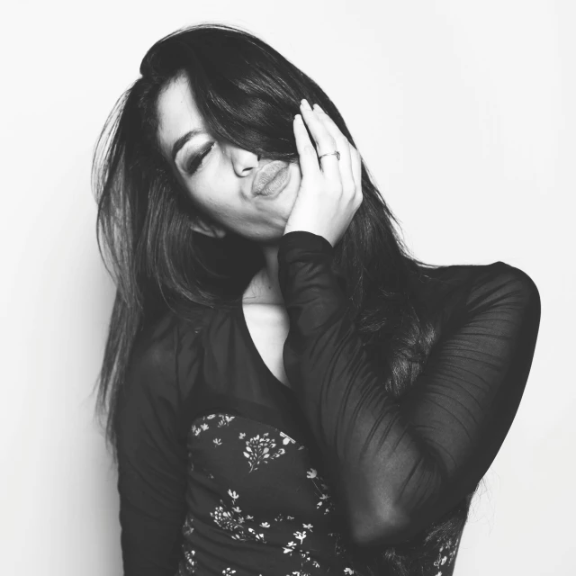 a black and white photo of a woman covering her eyes, tumblr, hurufiyya, sarah shahi, doing a sassy pose, black long hair!, portrait of ((mischievous))