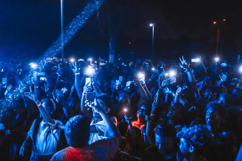 a crowd of people holding up their cell phones, by Niko Henrichon, pexels contest winner, graffiti, high blue lights, outdoor rave, blue and orange lighting, tiny details