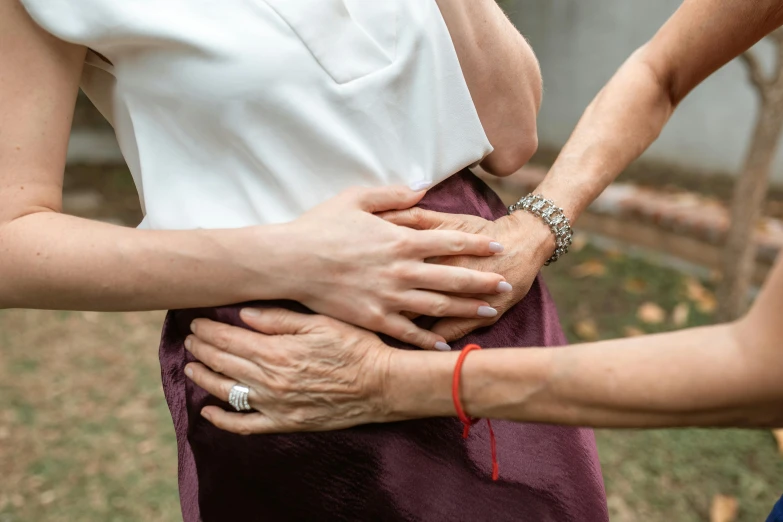 a woman putting a bracelet on another woman's hand, by Emma Andijewska, happening, hand on hips, cysts, tight wrinkled cloath, profile image