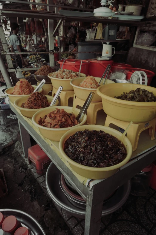 a number of bowls of food on a table, sumatraism, muddy colors, wet market street, low quality photo, square