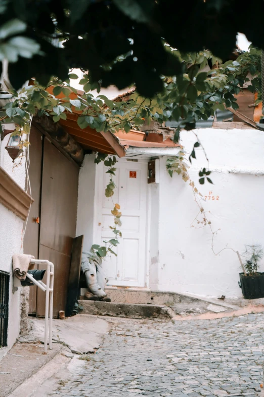 a person riding a bike down a cobblestone street, a picture, inspired by Elsa Bleda, trending on unsplash, renaissance, house on a hill, turkey, leaning on door, photographed on damaged film