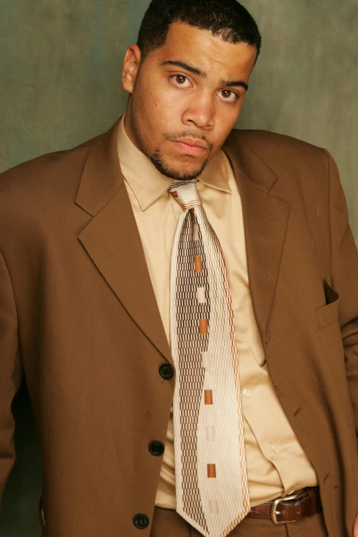 a man in a suit and tie posing for a picture, an album cover, inspired by Christopher Williams, wearing a worn out brown suit, jamal campbell, studio shoot, 2006 photograph