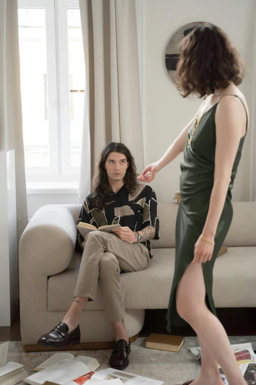 a woman standing next to a woman sitting on a couch, by Nina Hamnett, trending on unsplash, renaissance, male model, long dress, young male, ignant