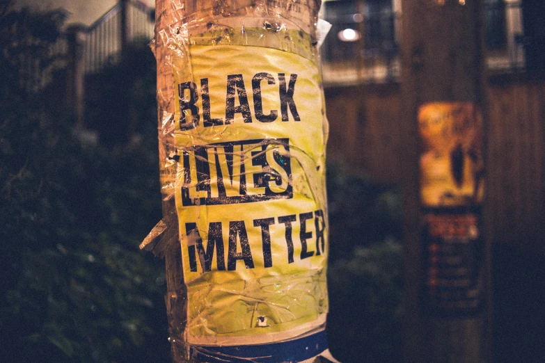 a pole with a sign on it that says black lives matter, pexels contest winner, decoration, black veins, night life, black. yellow