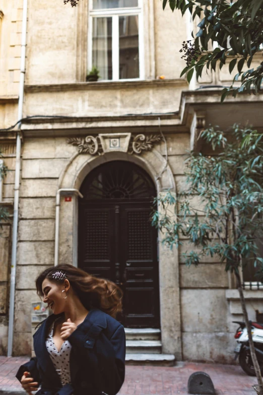 a woman walking down a sidewalk in front of a building, a photo, pexels contest winner, renaissance, flying hair, roma, lush surroundings, playful