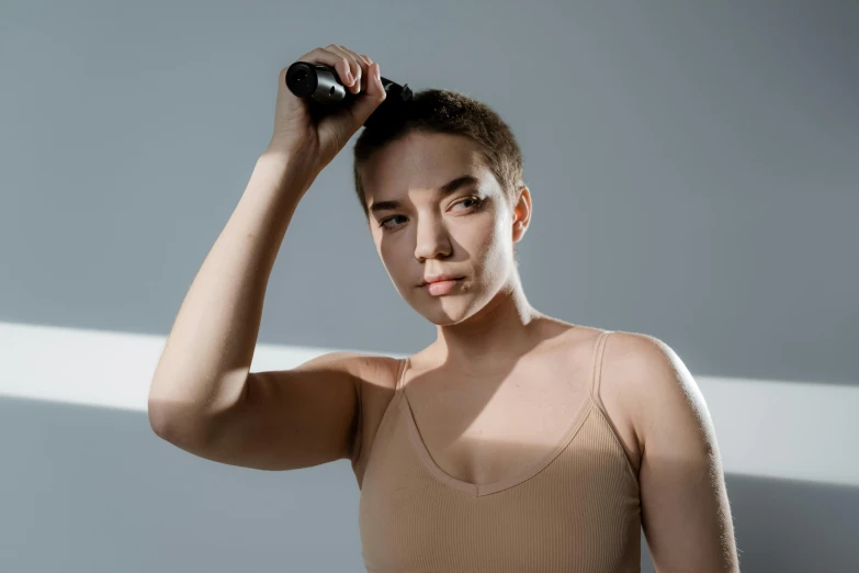 a woman holding a tennis racquet on top of her head, a portrait, trending on pexels, bauhaus, crew cut hair, detailed product image, hair floating covering chest, buzzed short dark hair