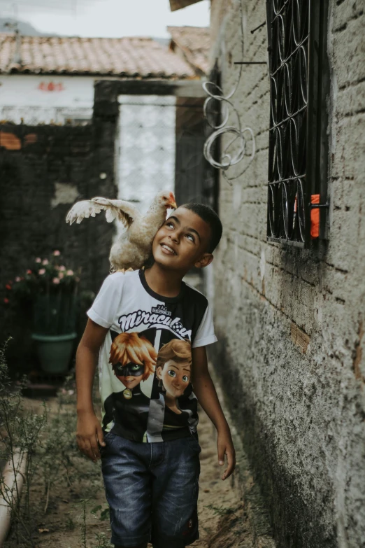 a young boy holding a bird on his shoulder, by Joze Ciuha, pexels contest winner, renaissance, location ( favela _ wall ), chicken dressed as an inmate, a still of a happy, on a farm