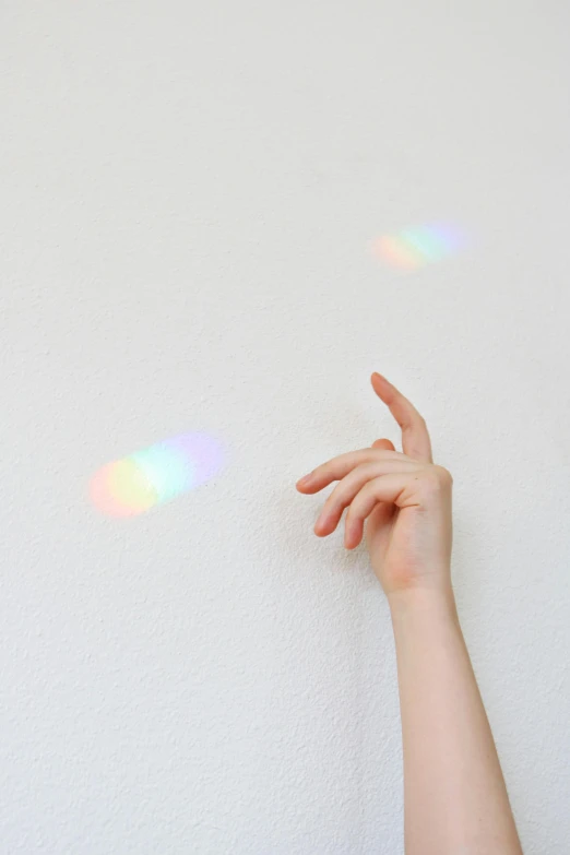 a close up of a person's hand near a wall, inspired by Gabriel Dawe, trending on pexels, holography, rinko kawauchi, holo sticker, silver small small small glasses, play of light