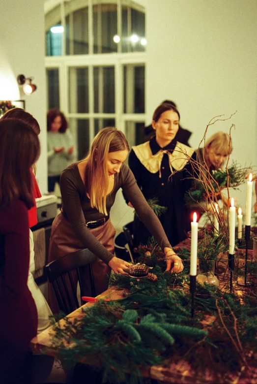 a group of people standing around a table with candles, pine, making of, profile image, decorations