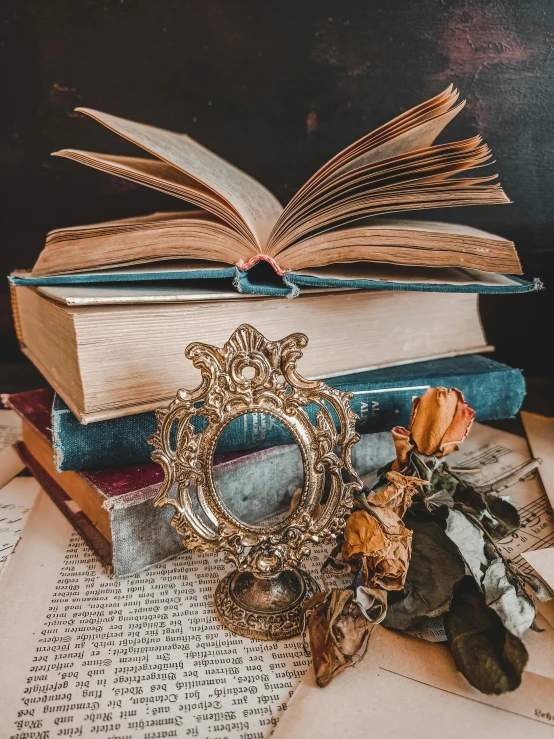 an open book sitting on top of a pile of books, a still life, by Isabel Naftel, pexels contest winner, neoclassicism, ornate metal gold headpiece, snapchat photo, vintage closeup photograph, mirror and glass surfaces