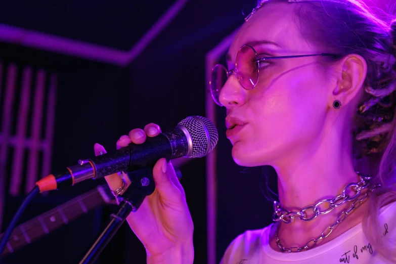 a woman in glasses singing into a microphone, an album cover, pexels, antipodeans, nightclub, lily frank, profile image, bella poarch