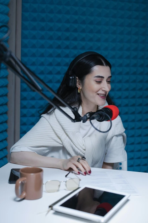 a woman sitting at a table in front of a microphone, inspired by Ion Andreescu, trending on reddit, in a studio, ayanamikodon and irakli nadar, uncropped, rachel weisz