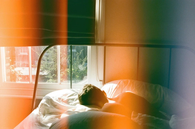 a person laying on a bed in front of a window, inspired by Elsa Bleda, unsplash, light and space, coloured film photography, sun glare, instagram post, ignant