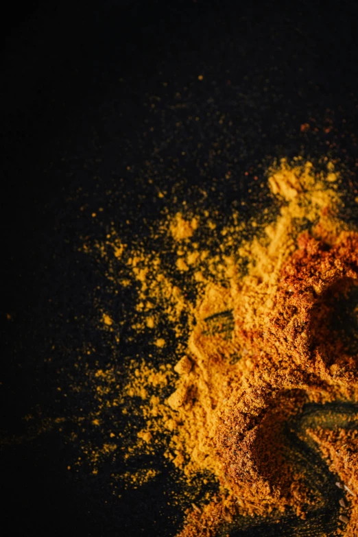 a teddy bear sitting on top of a pile of powder, spices, orange yellow ethereal, black and gold palette, zoomed in