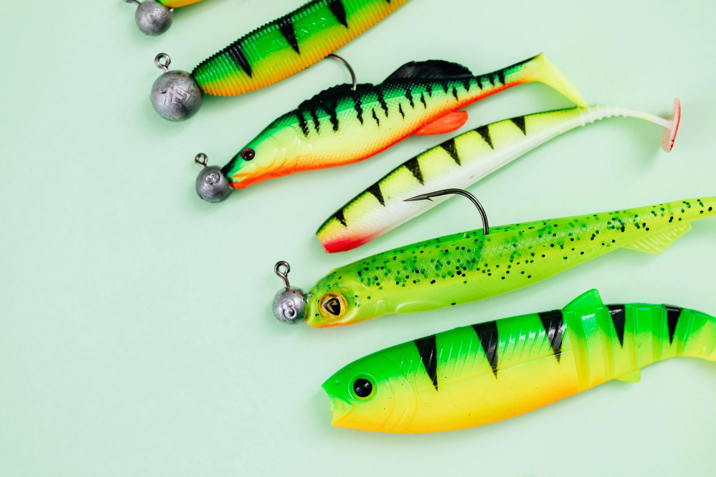 a group of fishing lures sitting next to each other, by Julia Pishtar, neon green, long hook nose, flat lay, mixed styles