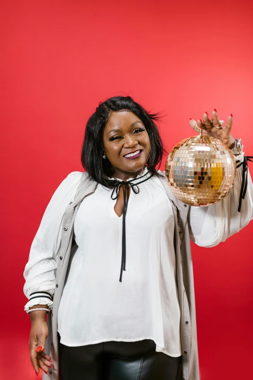 a woman in a white shirt holding a disco ball, style of mary jackson, in red background, holding it out to the camera, cheerful