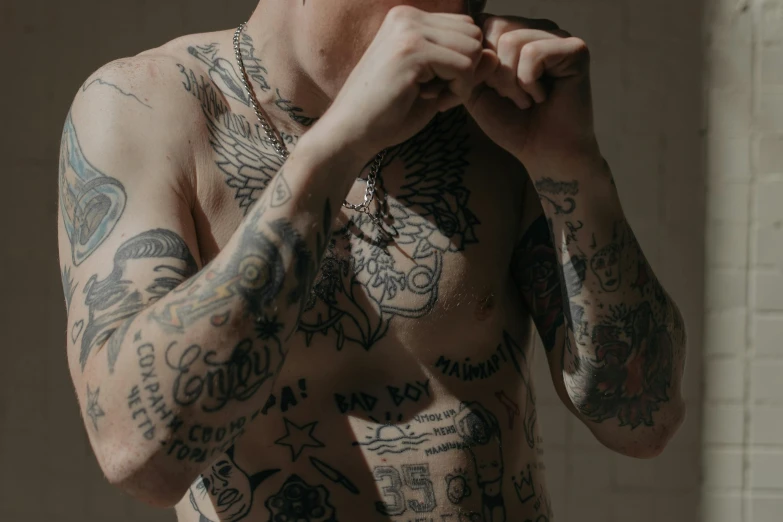 a man with tattoos is brushing his teeth, a tattoo, inspired by Seb McKinnon, trending on pexels, joe keery, arms covered in gang tattoo, chest coverd, full character body