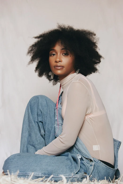 a woman sitting on top of a white rug, a portrait, featured on instagram, renaissance, long afro hair, wearing denim, ashteroth, no background