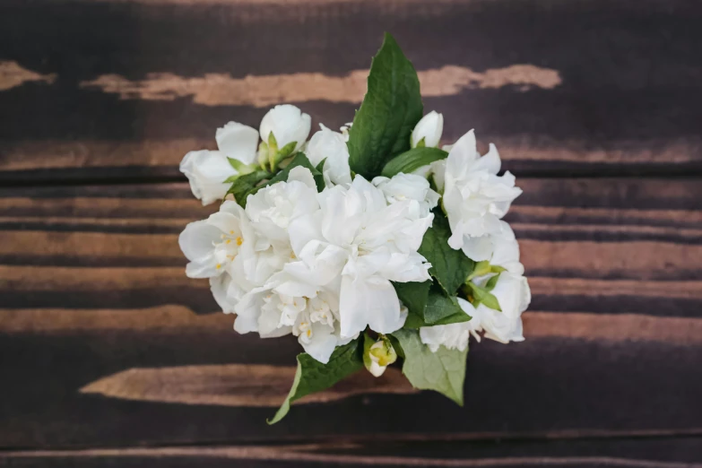 a bouquet of white flowers sitting on top of a wooden table, unsplash, renaissance, jasmine, high angle view, close-up photo